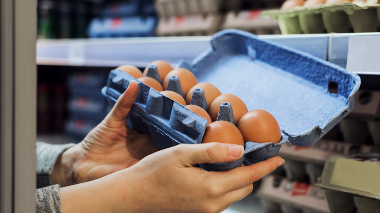 person holding egg carton in grocery store