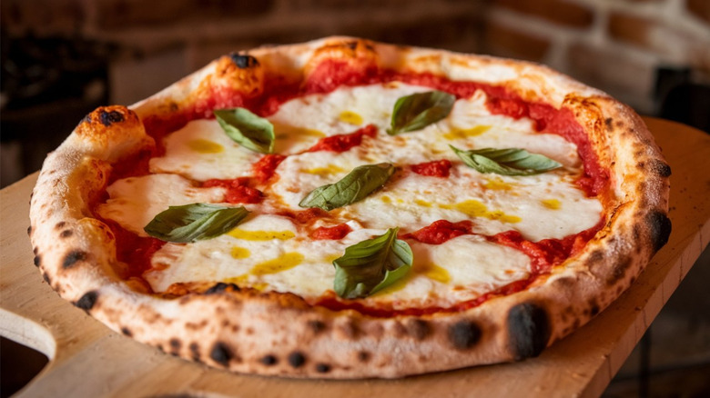 a freshly made Neapolitan pizza on wood paddle