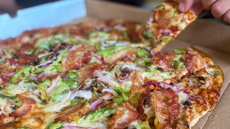 St. Louis style pizza from Imo's, a hand grabbing a slice