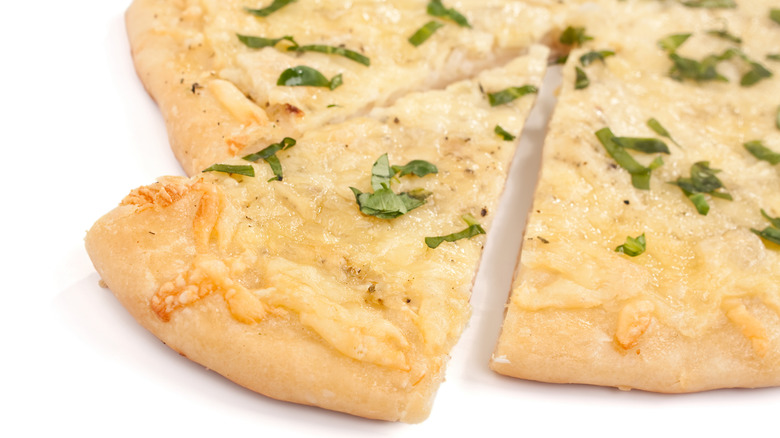 close-up of a white pizza on white backdrop, one slice being removed