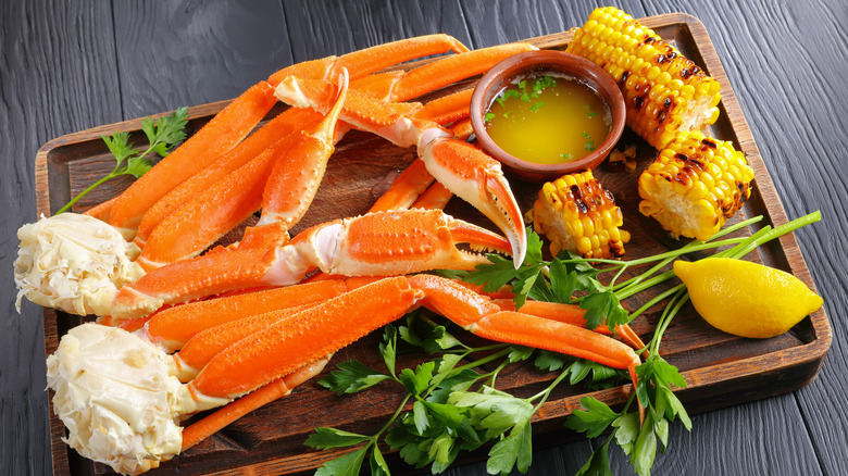 crab legs on tray with butter, lemon, and corn