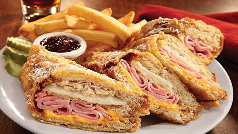 Bennigan's Monte Cristo sandwich served with jam, pickles, and fries.