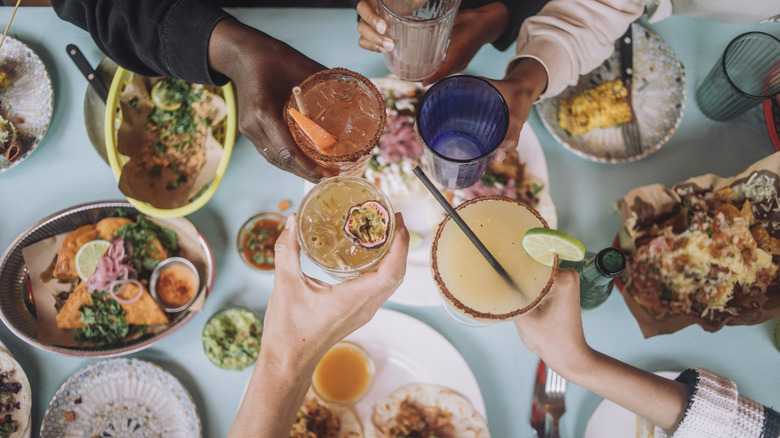 People toasting over restaurant table and plates of food