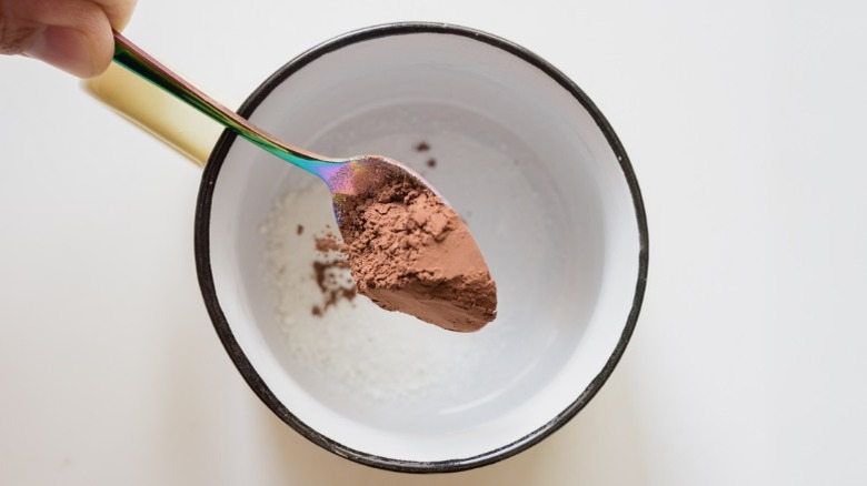 Spoon of cocoa powder dropped in a bowl