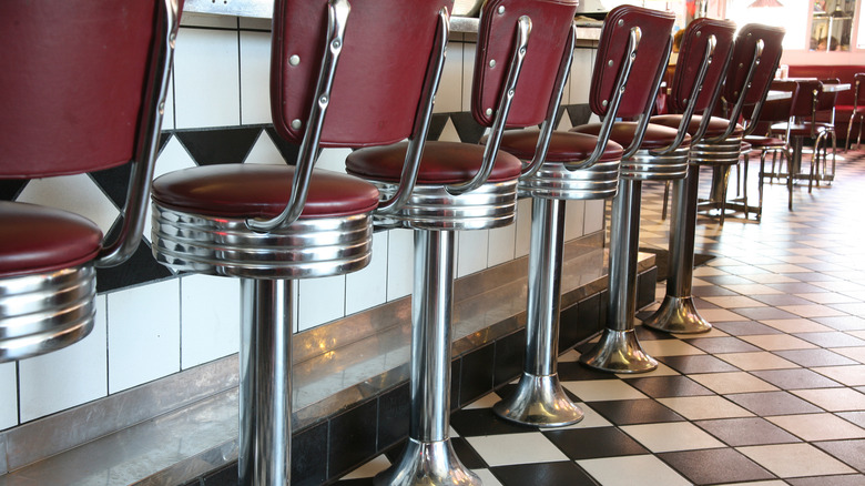 Black and white checkered floor and red diner stools