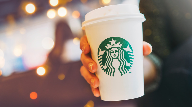 Hand holding white Starbucks cup