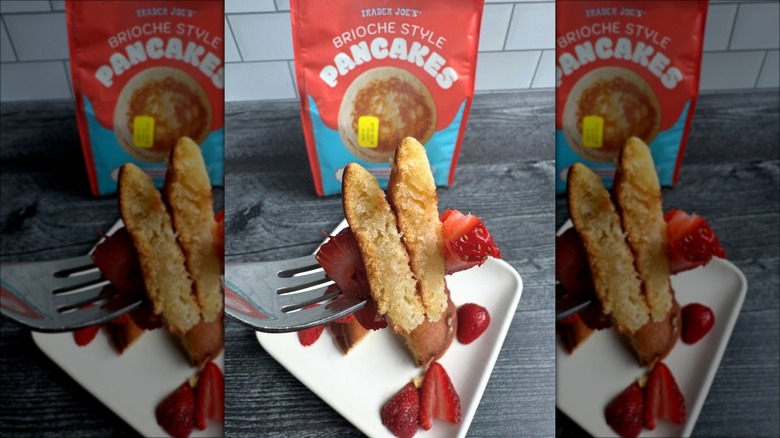 Two pieces of pancake and strawberries with a plate and bag of Trader Joe's brioche-style pancakes.