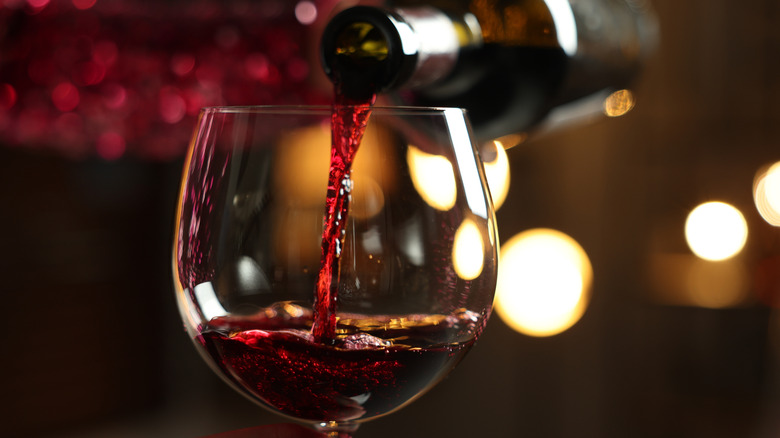 Red wine pouring from bottle into glass.