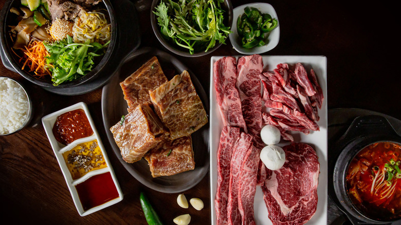 Korean BBQ set featuring marinated beef ribs, fresh vegetables, kimchi, and sauces