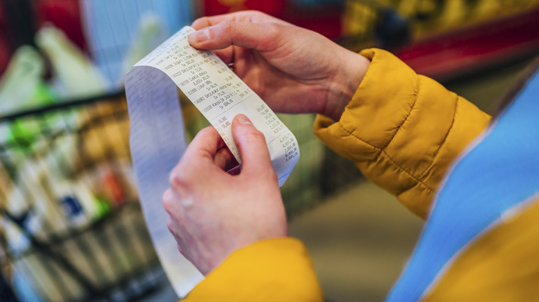 Two hands holding grocery store receipt