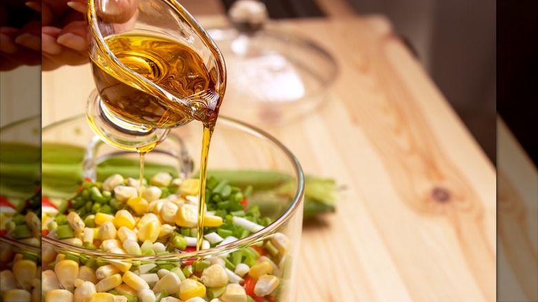 Person pouring dressing into corn salad