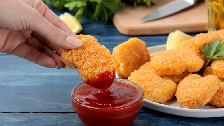 Person dipping chicken nuggets into sauce