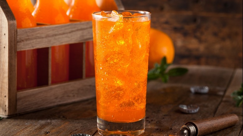 orange soda poured over ice in drinking glass