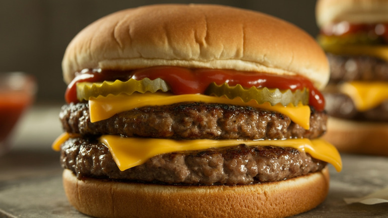 Double cheeseburger with pickles and ketchup on table.