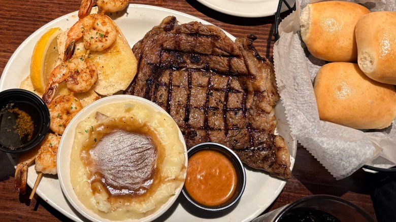 Dinner plate with steak, mashed potatoes, and appetizer in the midst of other foods at Texas Roadhouse.