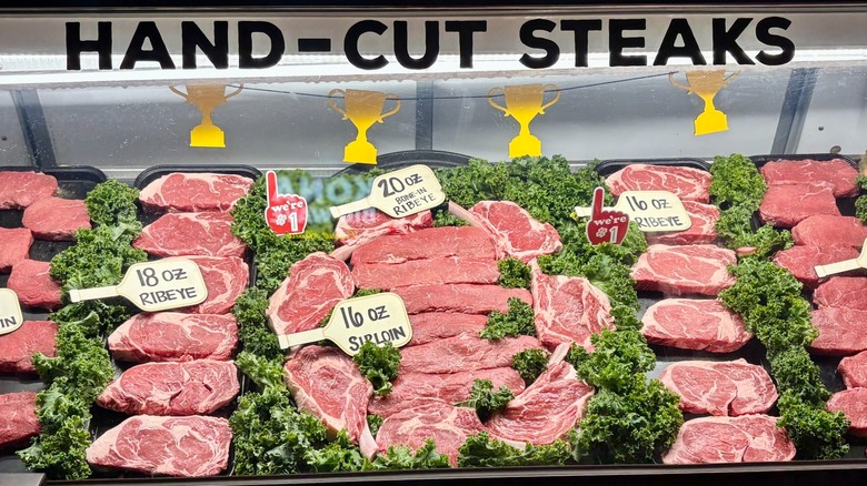 Display case at Texas Roadhouse with various sizes of raw steaks labeled and carved.