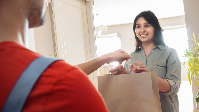 Woman receiving bag from delivery driver