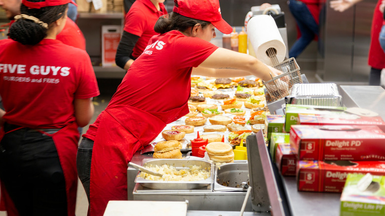 Staff making multiple burgers at a Five Guys restaurant.
