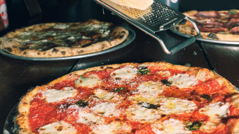 Hand grating cheese on pizza