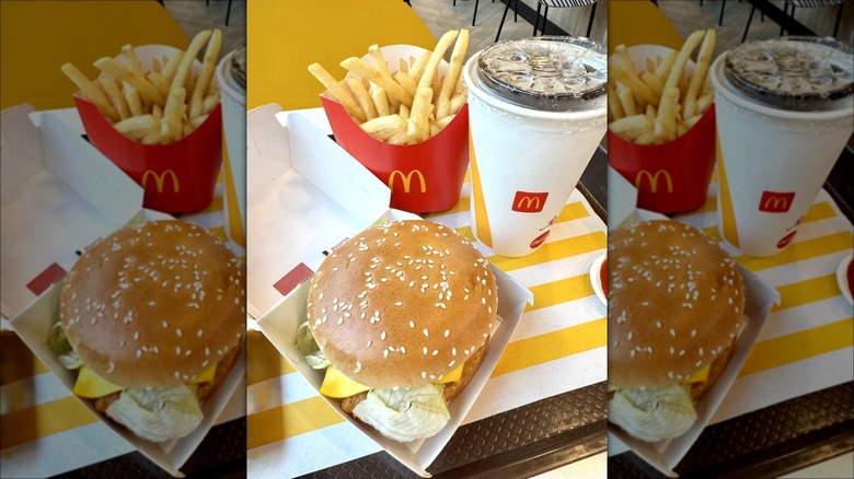 McDonald's cheeseburger, fries, and beverage on table at the restaurant.