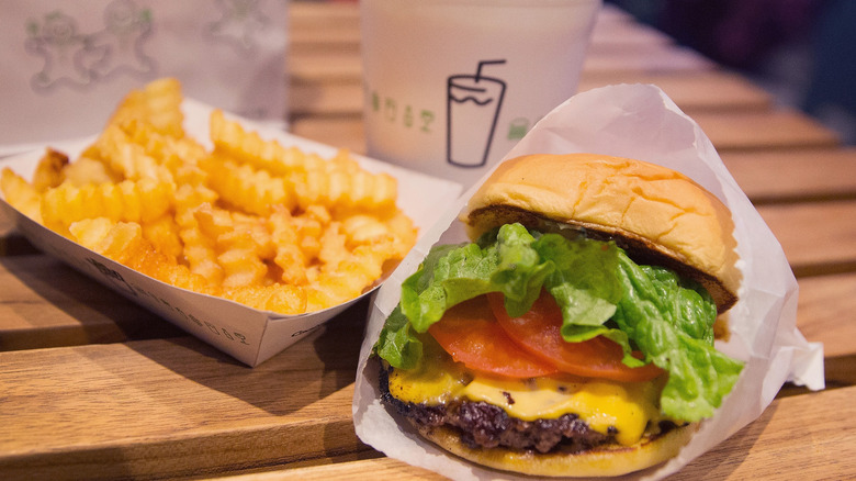 Cheeseburger, crinkly fries, and beverage on table at Shake Shack restaurant.