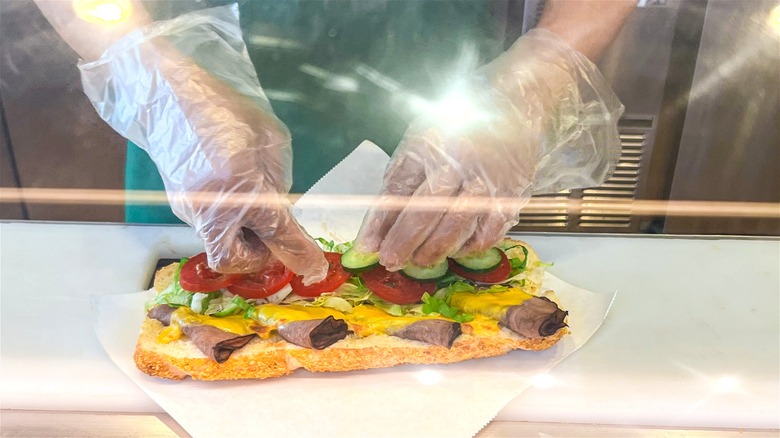 A Subway sandwich being customized.
