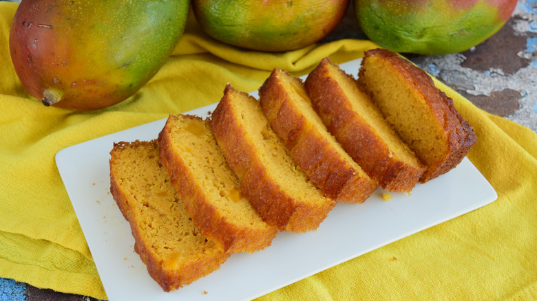 Slices of mango bread on a plate with mangoes