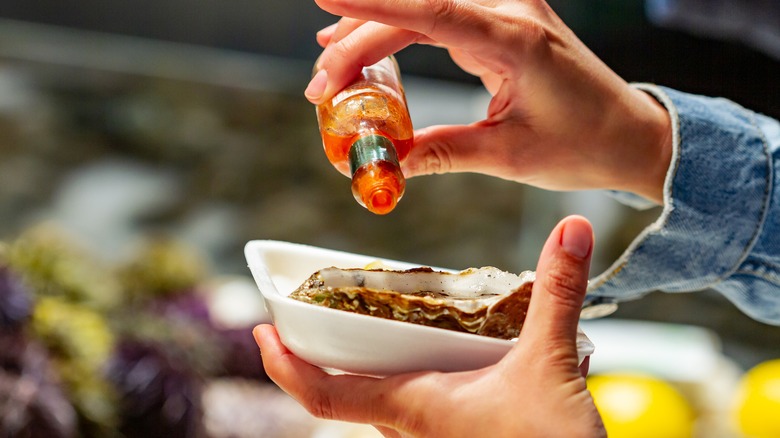 Person smothering oysters with sauce
