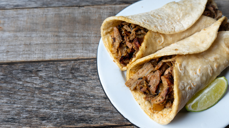 Tacos arabes on a white plate on a wooden table