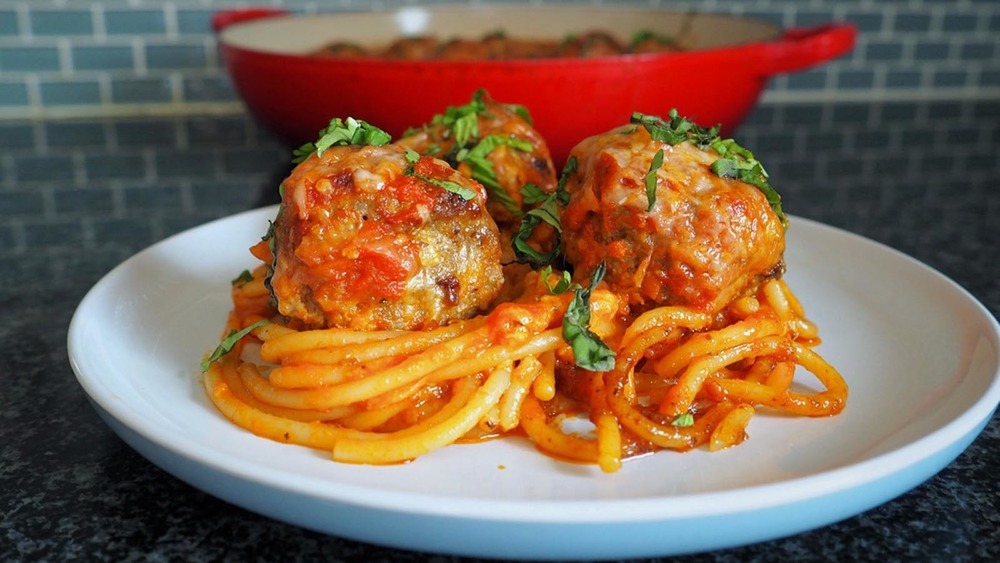Spaghetti and meatballs on a white plate on a counter