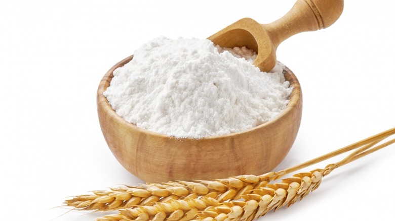 wooden bowl of flour with stalks of wheat