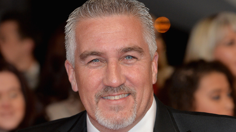 Paul Hollywood smiling wearing a black suit