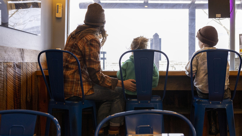 woman sits with children at small restaurant