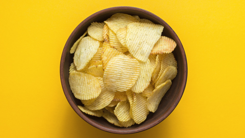 Bowl of potato chips on yellow background