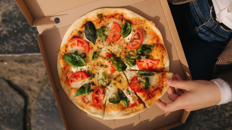 Person taking slice of pizza out of the box