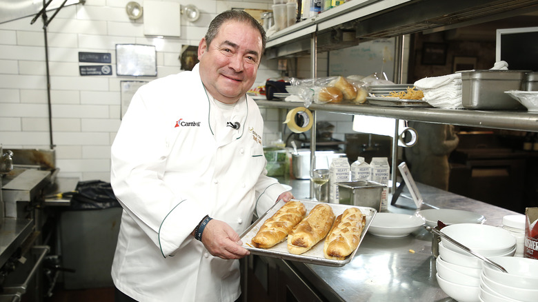 Emeril Lagasse holding a baking sheet and smiling