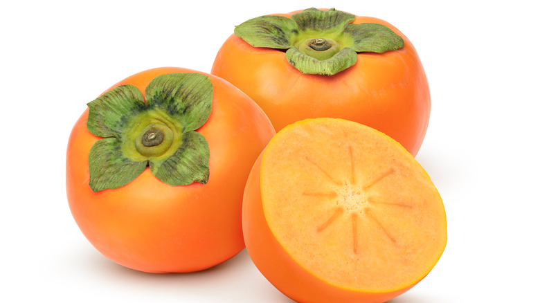 three persimmons against a white background