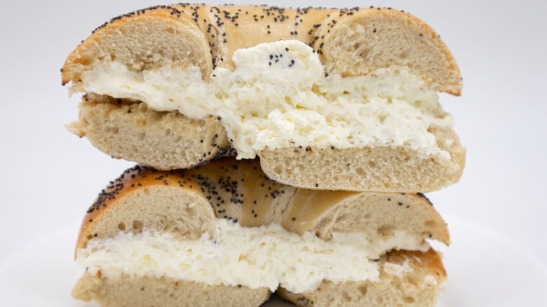 Poppy seed bagel with cream cheese cut in half.