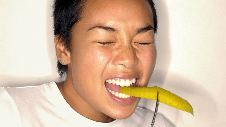 Person eating pickle on a fork
