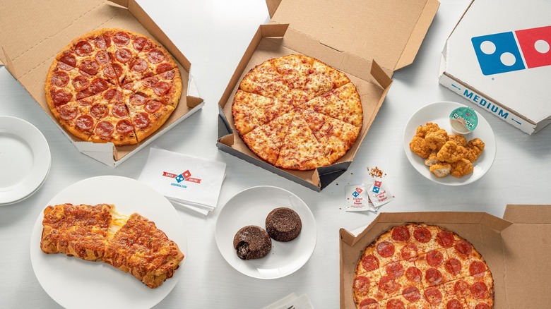 Three Domino's pizzas and assorted menu items on white surface.
