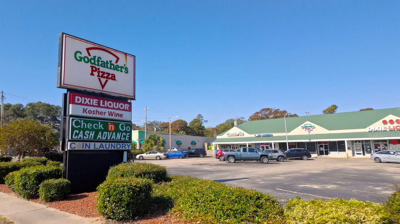 Streetside signage of a Godfather's Pizza in the foreground with the restaurant on the background.