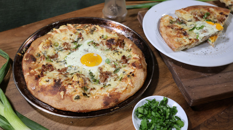 personal-sized sausage and gravy breakfast pizza on pan next to plate with two slices of the same