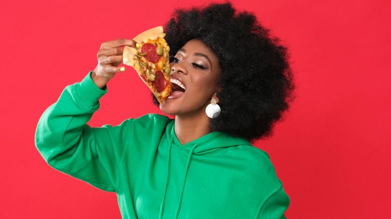 Woman eating pizza in green hoodie
