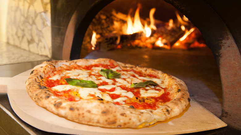 A pizza going into a fiery oven