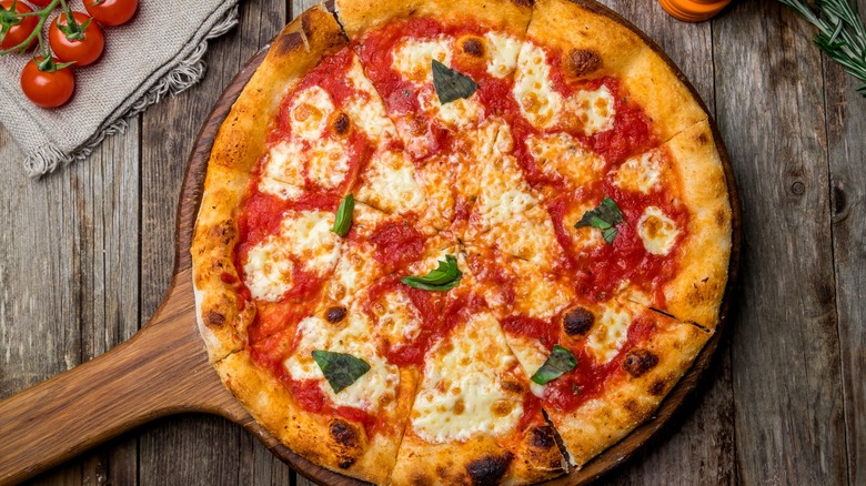 Freshly baked Margherita pizza on a wooden paddle.