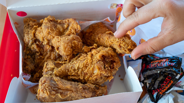 Person grabbing Popeyes chicken from box