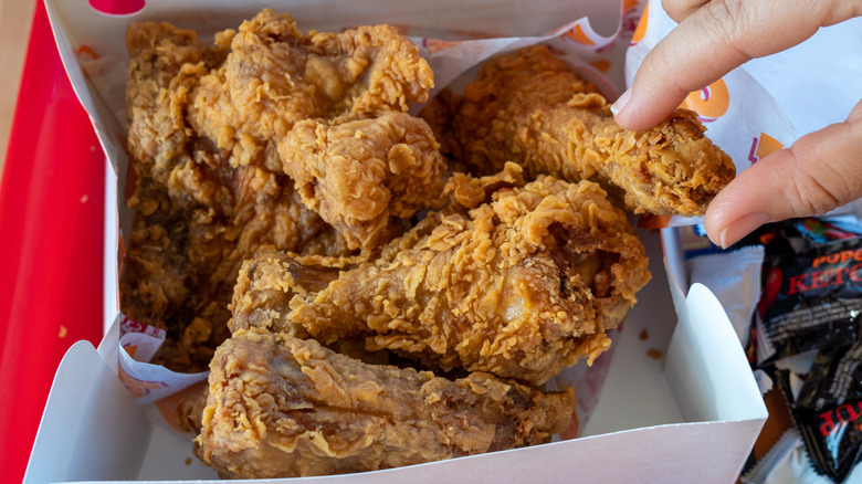 Hand grabbing Popeyes chicken piece