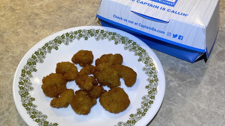 Captain D's popcorn shrimp on plate next to takeout box