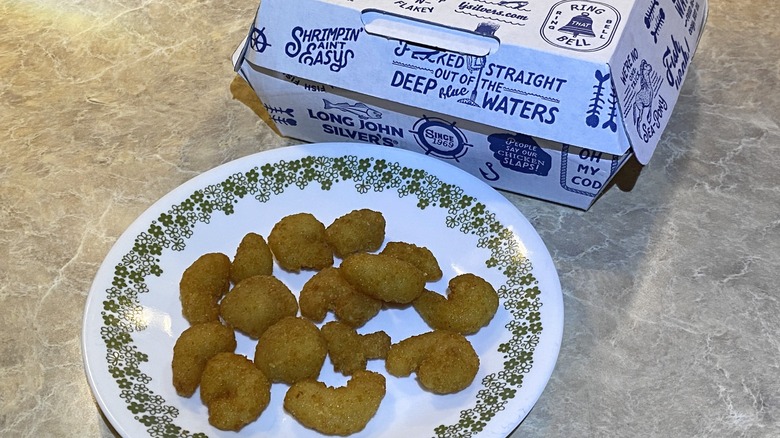 Long John Silver's popcorn shrimp on plate next to takeout container