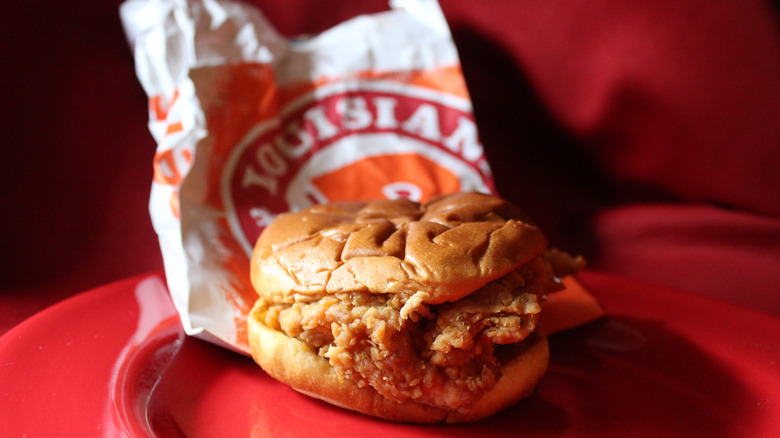 A Popeyes chicken sandwich on red background